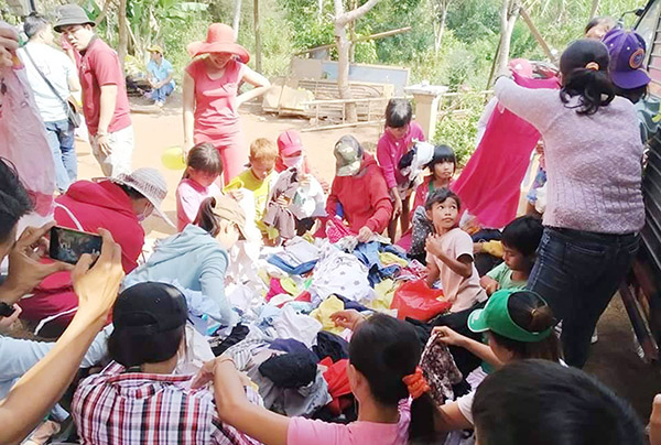 Người dân và các em nhỏ tại khu dân tộc Chơ Ro, xã Tây Hòa, huyện Trảng Bom chọn lựa quần áo cũ do Nhóm thiện nguyện Hoa Mặt Trời quyên góp gửi tặng. Ảnh: Hồ Thảo