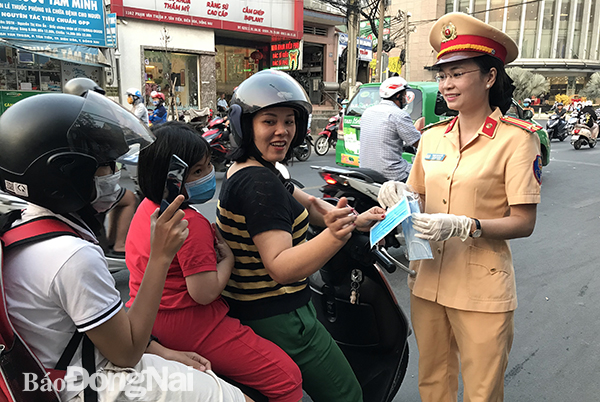 Bà Phạm Thị Huyền, Phó đội trưởng Đội CSGT Biên Hòa phát khẩu trang cho người tham gia giao thông
