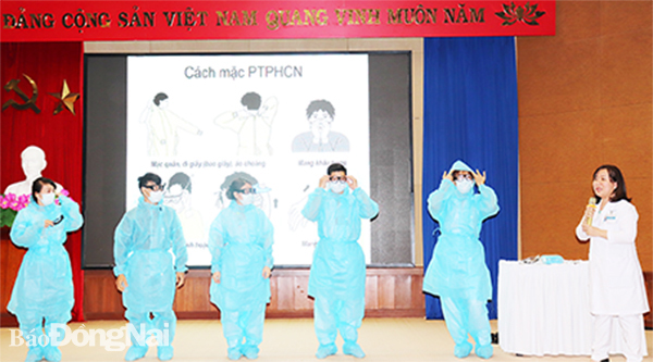 Nhân viên y tế Bệnh viện Đa khoa Đồng Nai được tập huấn cách mặc đồ bảo hộ đúng cách khi tiếp xúc, điều trị cho bệnh nhân nghi ngờ/nhiễm Covid-19. Ảnh: H.Dung