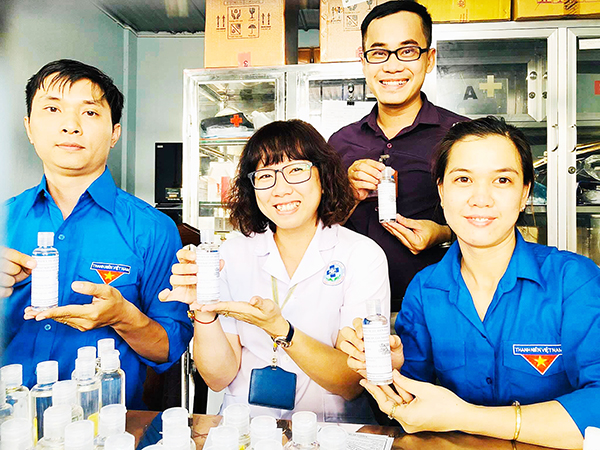 Anh Trần Duy Bảo (hàng sau) và các nhân viên y tế Trung tâm Y tế TP.Biên Hòa pha chế dung dịch rửa tay sát khuẩn phòng dịch bệnh 