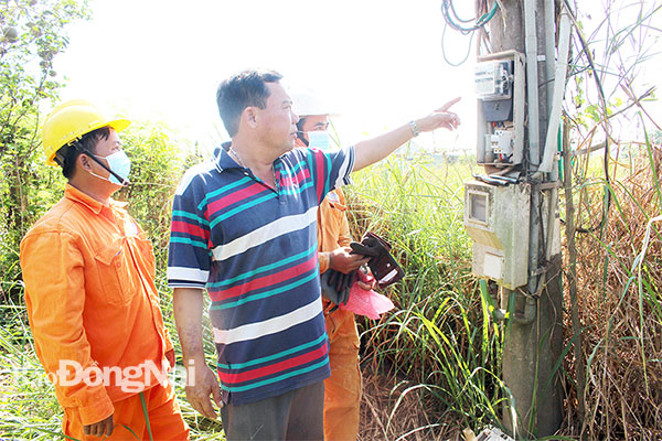 Người dân cùng cán bộ ngành Điện đi kiểm tra công tơ điện ở xã Sông Trầu, H.Trảng Bom ngày 13-5. Ảnh: L.An