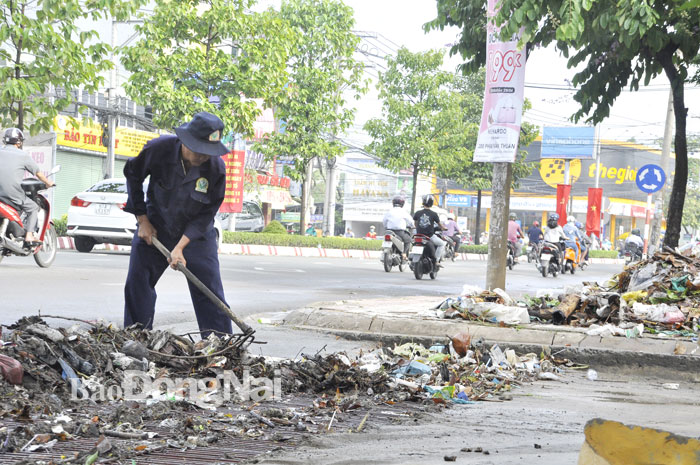 Công nhân vệ sinh môi trường thu dọn rác thải tại các nắp thoát nước sau mưa lớn khu vực trước Sở TN-MT (đường Đồng Khởi, TP.Biên Hòa)