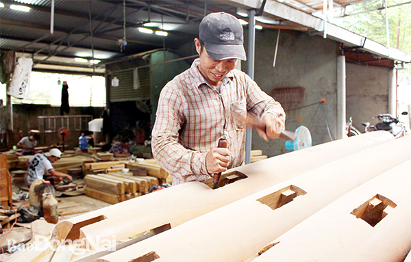 Anh Lê Văn Toàn (quê ở H.Hải Lăng, tỉnh Quảng Trị) thợ làm nhà gỗ ở H.Xuân Lộc đang thực hiện chạm trổ ở cột nhà gỗ. H.Đình