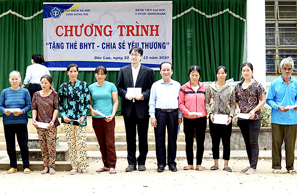 Đại diện lãnh đạo Bảo hiểm xã hội tỉnh và Bệnh viện Đại học y dược Shing Mark trao tặng thẻ bảo hiểm y tế cho người dân xã Đắc Lua (H. Tân Phú). Ảnh: Bệnh viện cung cấp