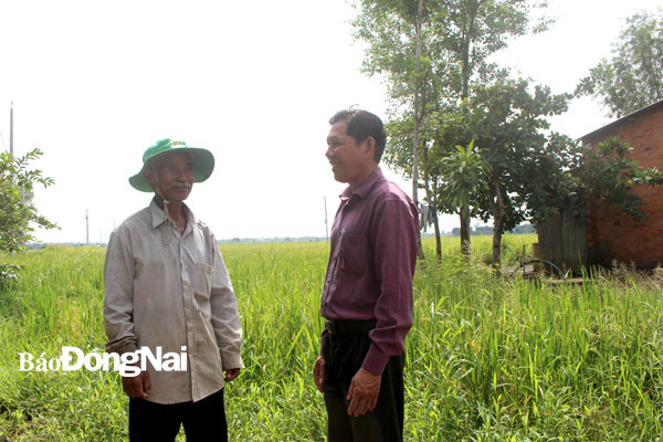 Già làng Hùng Văn Xứng (trái) cùng cán bộ xã Xuân Phú trao đổi công việc