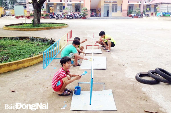 Các em học sinh Trường tiểu học Nguyễn Huệ (xã Xuân Phú, H.Xuân Lộc) sơn lại hàng rào phân luồng xe máy của phụ huynh đến trường đưa đón học sinh. Ảnh: C.Nghĩa