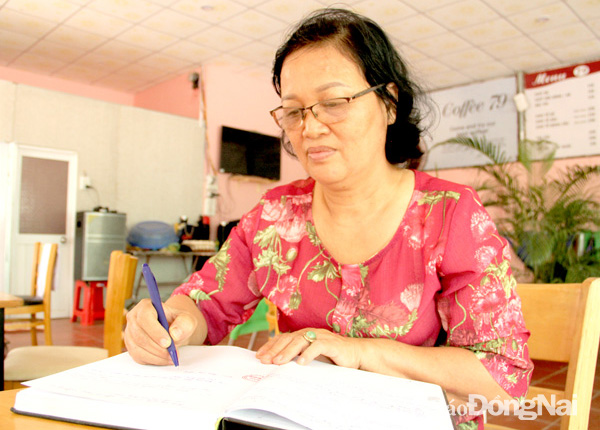 Bà Nguyễn Thị Mải đang rà soát nội dung trong sổ ghi chép những khoản đóng góp trợ giúp nạn nhân chất dộc da cam/dioxin. Ảnh: Văn Truyên