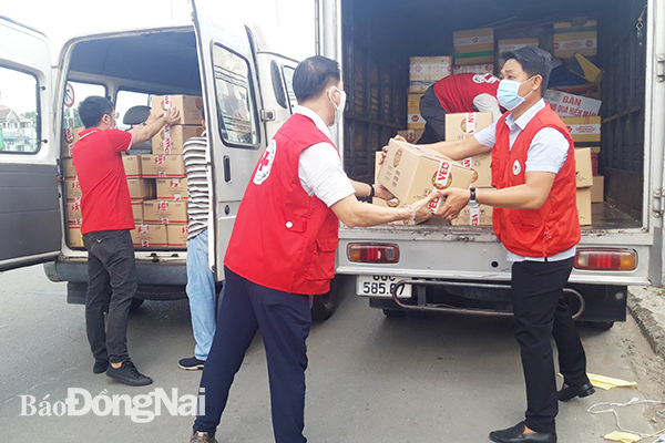 Các thành viên Hội Chữ thập đỏ tỉnh vận chuyển nông sản và thực phẩm lên xe để vận chuyển lên hỗ trợ người dân TP.HCM