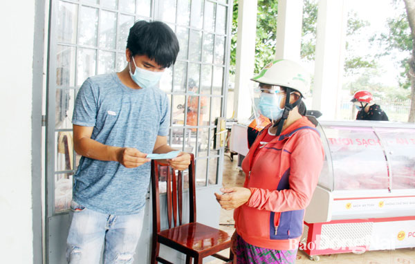 Nhân viên tại một điểm bán hàng bình ổn giá ở Nhà văn hóa KP.3 (P.Trảng Dài) kiểm phiếu đi chợ, phân luồng người dân trước khi vào mua sắm. Ảnh: H.Quân