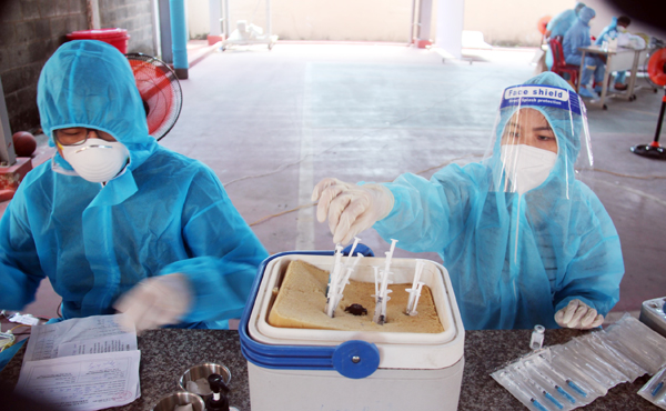 5. Để việc tiêm vaccine ngừa Covid-19 được thực hiện liên tục, đảm bảo tiến độ, ngoài điều dưỡng trực tiếp tiêm còn có nhân viên lấy vaccine sẵn (Ảnh chụp tại điểm tiêm ngừa ở Trường THPT Ngô Quyền)