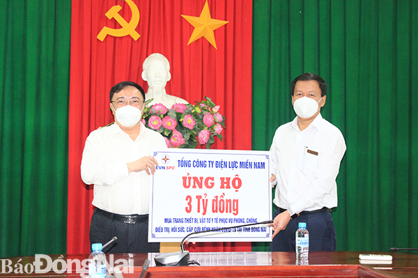 Ông Nguyễn Ngọc Thành, Giám đốc Công ty TNHH MTV Điện lực Đồng Nai (phải) trao tặng bảng tượng trưng số tiền 3 tỷ đồng cho lãnh đạo Sở Y tế