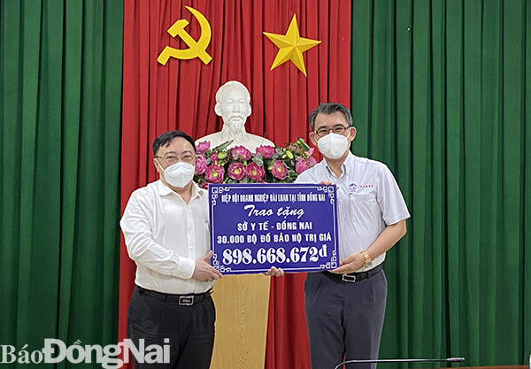 Lãnh đạo Sở Y tế (bên trái) tiếp nhận bảng tượng trưng 30 ngàn bộ đồ bảo hộ cá nhân do Hiệp hội Thương mại Đài Loan tỉnh Đồng Nai trao tặng