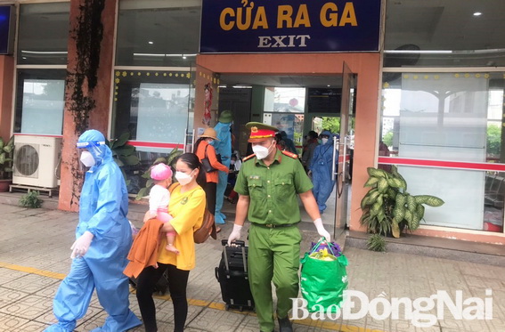 Lực lượng Công an và nhân viên y tế TP.Biên Hòa xách hành lý và hỗ trợ người dân lên tàu về Quảng Bình