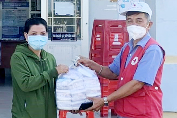 Ông Nguyễn Văn Trường, xã Gia Canh trao tặng khẩu trang cho đại diện Trạm y tế xã Ngọc Định, H.Định Quán. Ảnh: Quang Tân