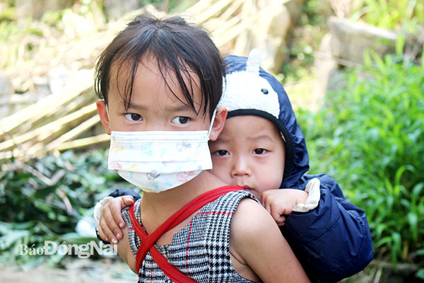 Trẻ em vùng núi đá Lũng Chinh (H.Mèo Vạc, tỉnh Hà Giang) quen với việc đèo em đi bộ đến trường, đi nương. Ảnh: Đoàn Phú