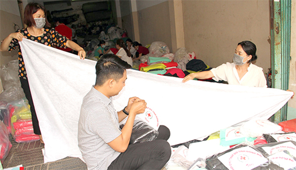 Các thành viên của Hội Chữ thập đỏ tỉnh đóng gói vải để chuẩn bị trao tặng cho người dân hoàn cảnh khó khăn nhân Tháng Nhân đạo sắp tới