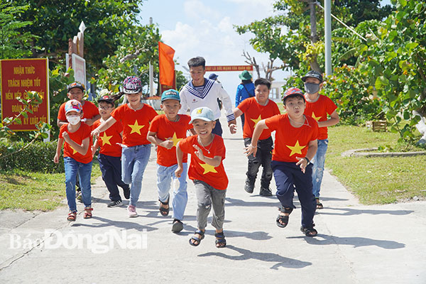 8. Học sinh Trường tiểu học Song Tử Tây vui đùa với chú hải quân trên con đường được đổ bê tông sạch sẽ trên xã đảo