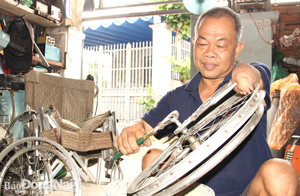 Ông Lê Thành Công (P.Trảng Dài, TP.Biên Hòa) sửa xe lăn cho người khuyết tật. Ảnh: S.Thao