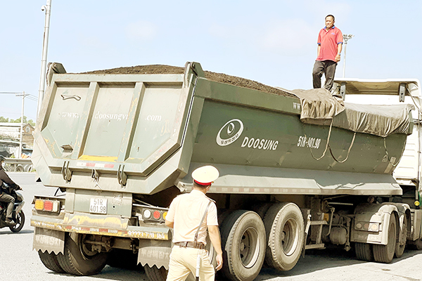 Đội Cảnh sát giao thông số 1 (Phòng Cảnh sát giao thông Công an tỉnh) yêu cầu tài xế tháo bạt, để lộ phần hàng (than) đang chở vượt quá chiều cao xếp hàng cho phép