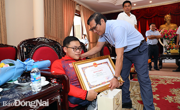 Phó chủ tịch UBND tỉnh Nguyễn Sơn Hùng tặng Bằng khen của UBND tỉnh cho VĐV Huỳnh Ngọc Phụng. Ảnh: Huy Anh