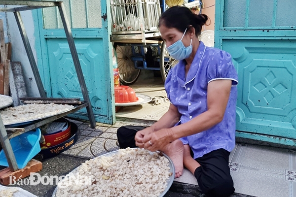 Bà Vũ Thị Huyền, ở trọ tại P.An Bình (TP.Biên Hòa) làm thêm nghề phơi cơm khô ngoài nghề bán vé số để có thêm thu nhập. Ảnh: L.MAI