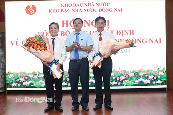 Chủ tịch UBND tỉnh Cao Tiến Dũng tặng hoa chúc mừng Giám đốc KBNN Đồng Nai Nguyễn Văn Biểu (bìa phải) và ông Phan Đức Ánh chuyển làm Giám đốc KBNN Bình Dương. Ảnh: Ngọc Liên