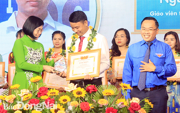 Phó chủ tịch UBND tỉnh Nguyễn Thị Hoàng (bìa trái) và Bí thư Tỉnh đoàn Nguyễn Minh Kiên (bìa phải) trao hoa và bằng khen cho các nhà giáo trẻ tiêu biểu